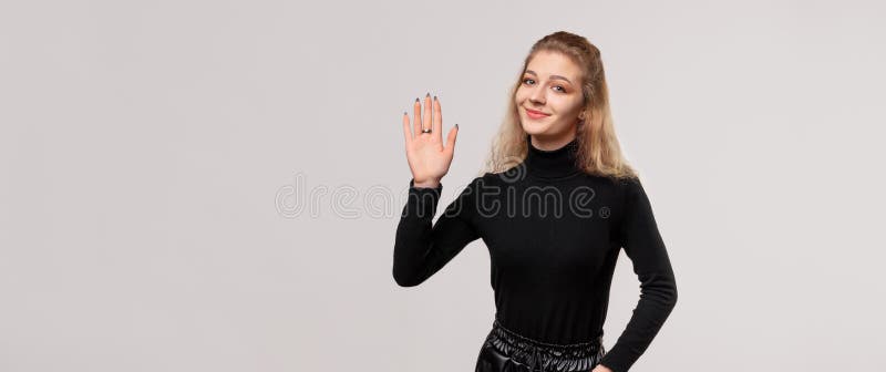 金发女孩用手问候，表情愉快，表示五个手指友好的欢迎手势. 广告位置 图库摄影