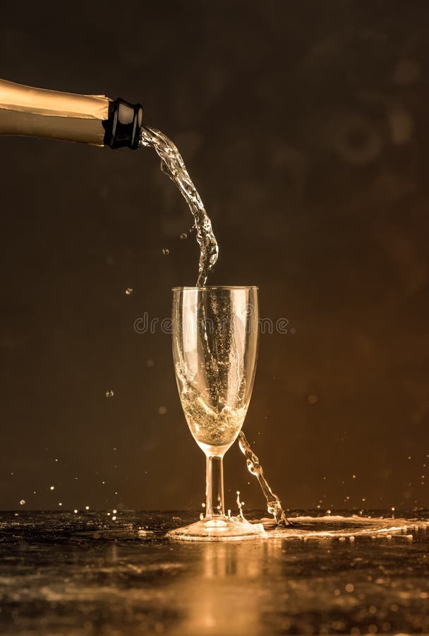 金黄香槟从瓶倾吐了入玻璃，可看见的下落、泡影和飞溅