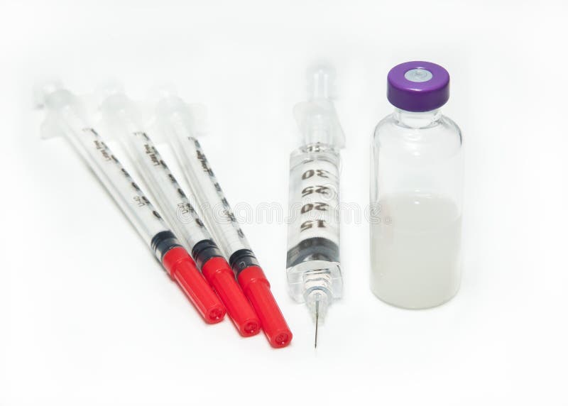 Three capped needles, one uncapped needle, beside a vial of vaccine. Three capped needles, one uncapped needle, beside a vial of vaccine.