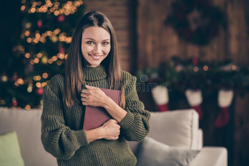 针织套头衫中正面开朗的棕色头发女孩的特写照片,在小说中欣赏她欢快的圣诞节 免版税库存图片 针织套头衫中正面开朗的棕色头发女孩的特写照片,在小说中欣赏她欢快的圣诞节 免版税库存图片