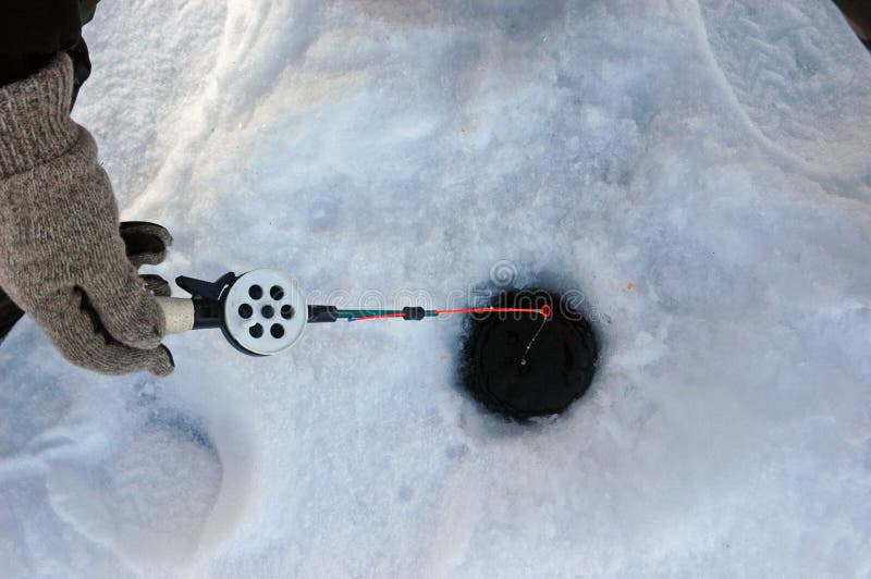 Fisherman holding a winter fishing tackle on the stood Krasnoyarsk water basin. Fisherman holding a winter fishing tackle on the stood Krasnoyarsk water basin.