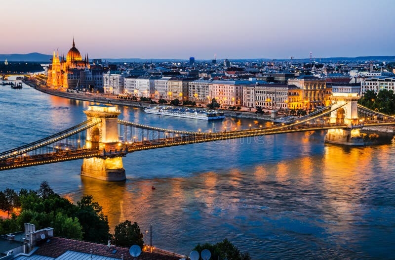 Budapest, Hungary. Szechenyi or Chain Bridge is a suspension bridge on river Danube, with Orszaghaz Parliament building, night lights. Budapest, Hungary. Szechenyi or Chain Bridge is a suspension bridge on river Danube, with Orszaghaz Parliament building, night lights.