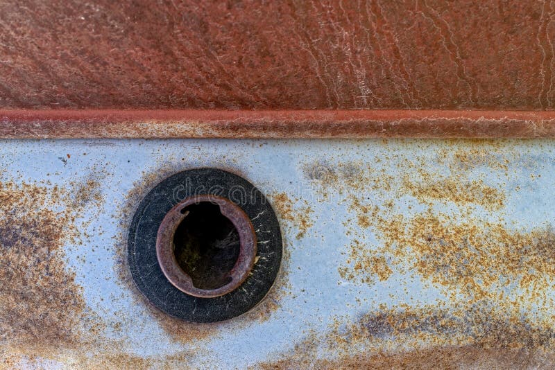 The uncapped gas tank opening of a rusty antique car. The uncapped gas tank opening of a rusty antique car