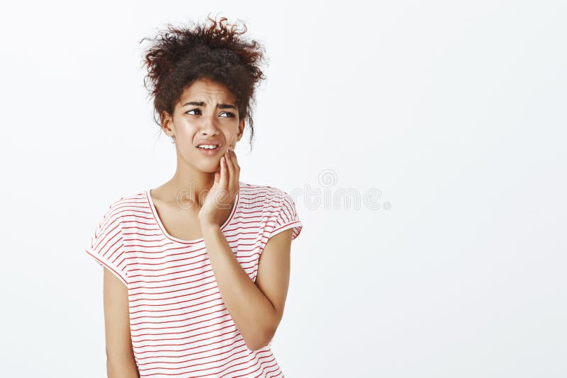 镶边T恤杉的混乱的生气逗人喜爱的女朋友,皱眉和做鬼脸从痛苦的感觉,在面颊的藏品手 免版税库存图片 镶边T恤杉的混乱的生气逗人喜爱的女朋友,皱眉和做鬼脸从痛苦的感觉,在面颊的藏品手 免版税库存图片