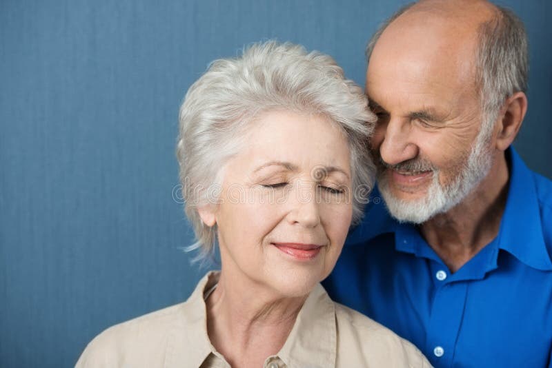 Elderly couple share a tender moment of love as they stand close together with their eyes closed in contentment and bliss. Elderly couple share a tender moment of love as they stand close together with their eyes closed in contentment and bliss