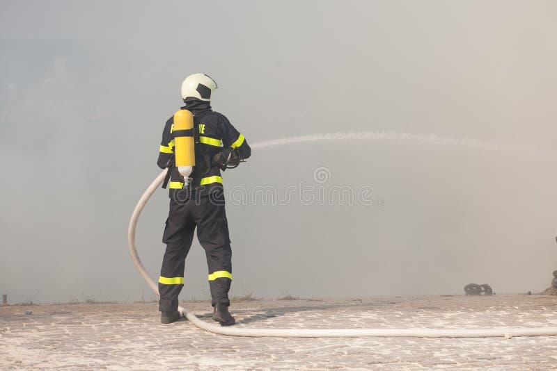 Firefighter in protective suit works with water hose. Fighting for a fire. Firefighter in protective suit works with water hose. Fighting for a fire