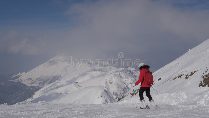 阳光明媚的冬日，优雅女子滑雪者在滑雪胜地滑雪