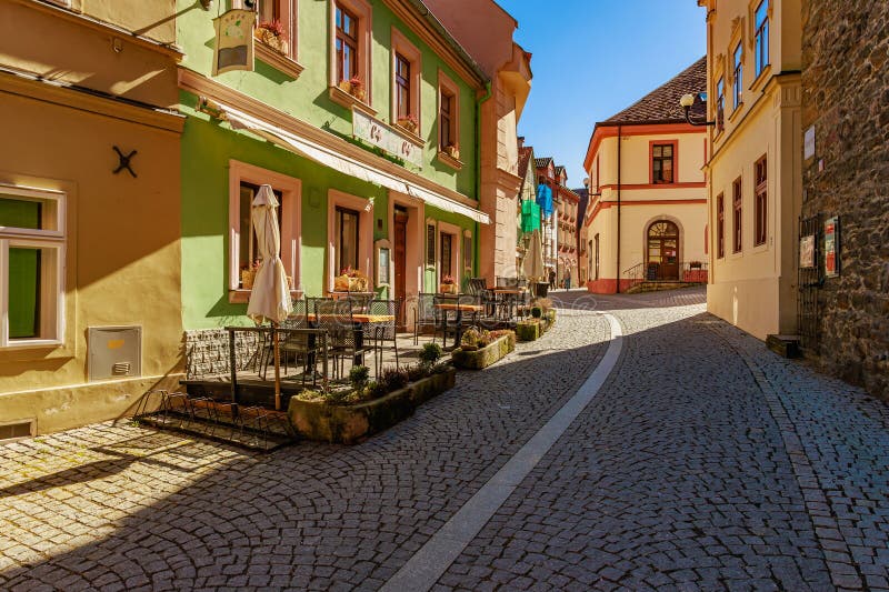 阳光明媚的欧洲鹅卵石街道，有户外咖啡馆和色彩缤纷的建筑。2025年3月18日，洛凯特，捷克共和国 图库摄影