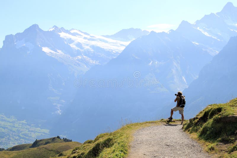 Walking from the mount of Mannlichen to the Kleine Scheidegg in the Swiss mountains of the Bernese Oberland a photographer is shooting the overwhelming nature of this landscape. From left to right: the Wetterhorn (3701 m), the Schreckhorn (4078 m) and a part of the slope of the Mattenberg (3104 m). In the valley you can still see a part of the village of Grindelwald. Walking from the mount of Mannlichen to the Kleine Scheidegg in the Swiss mountains of the Bernese Oberland a photographer is shooting the overwhelming nature of this landscape. From left to right: the Wetterhorn (3701 m), the Schreckhorn (4078 m) and a part of the slope of the Mattenberg (3104 m). In the valley you can still see a part of the village of Grindelwald.