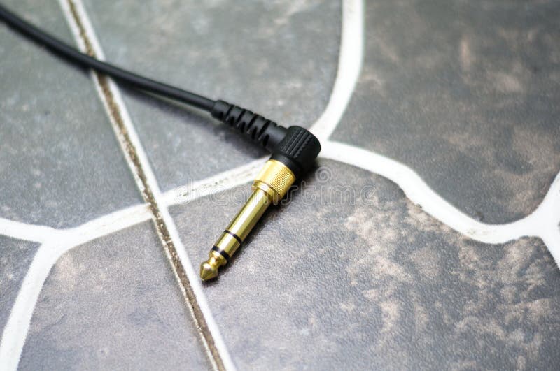 Close-up Shot Of 3.5mm Audio Jack Cable With 6.35mm Converter Attached. The picture shot in a ceramic. Close-up Shot Of 3.5mm Audio Jack Cable With 6.35mm Converter Attached. The picture shot in a ceramic