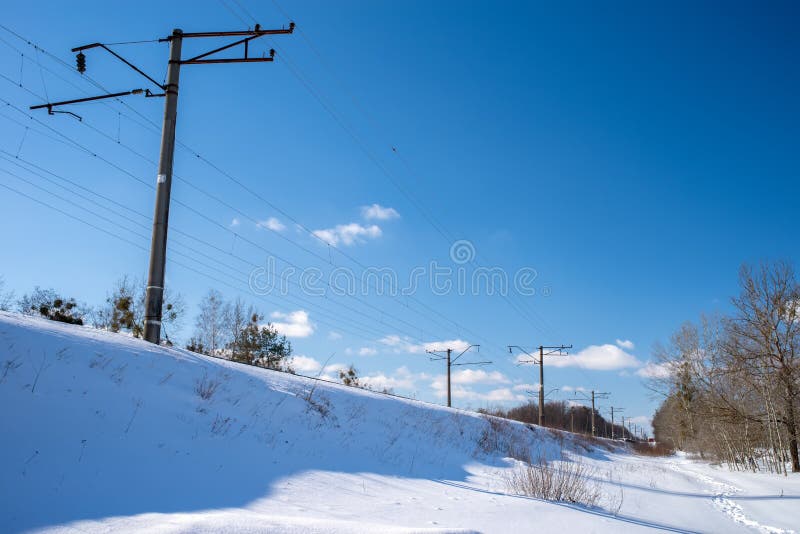 An electrified railway on a trackbed under the snow. Electric poles along the railway. An electrified railway on a trackbed under the snow. Electric poles along the railway