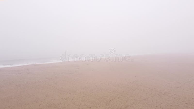 雾天在沙滩上行走的无法辨认的人