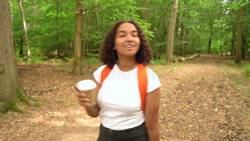 青少年混合种族非洲裔女孩在森林里徒步时带着橙色背包智能手表