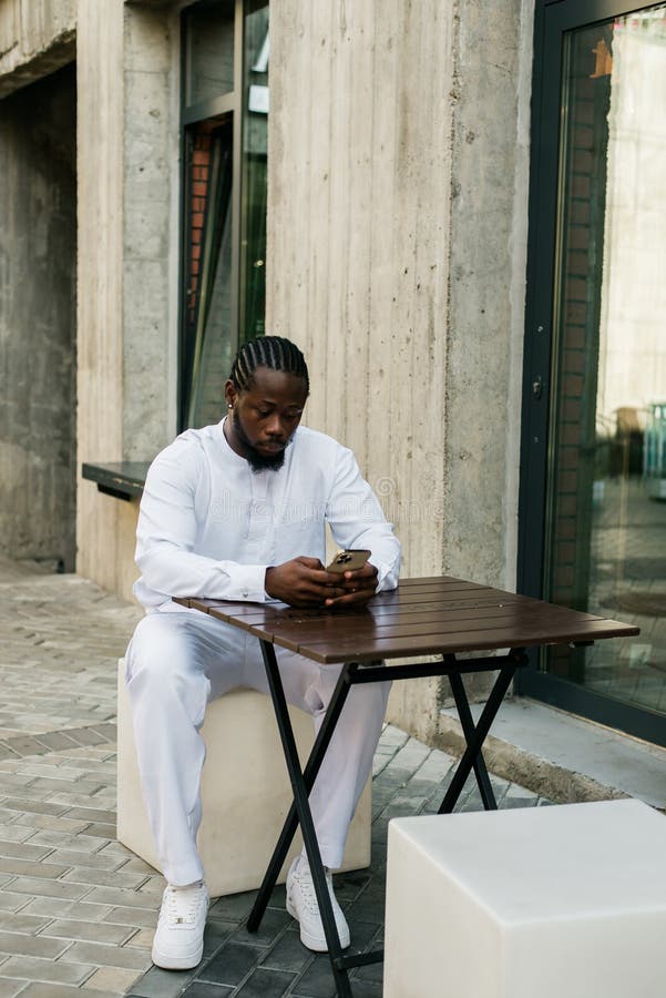 African american man checks cell phone in the street cafe in summer day. Millennial generation and gen z people. Social networks and dating app. African american man checks cell phone in the street cafe in summer day. Millennial generation and gen z people. Social networks and dating app