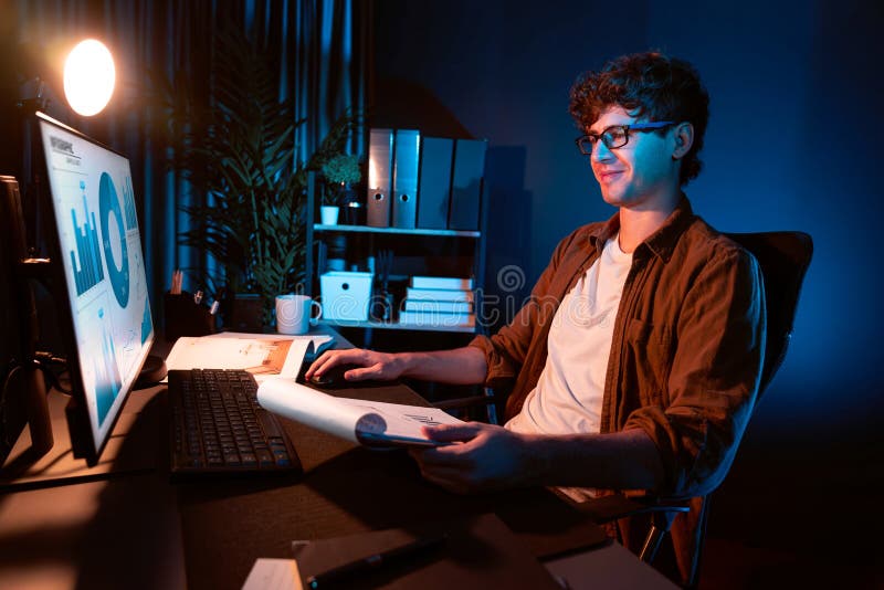 Young businessman reading design thinking on paper for new project surround work desk at neon light modern office. Thinking new next job sketching on notebook before sending present via email. Gusher. Young businessman reading design thinking on paper for new project surround work desk at neon light modern office. Thinking new next job sketching on notebook before sending present via email. Gusher.