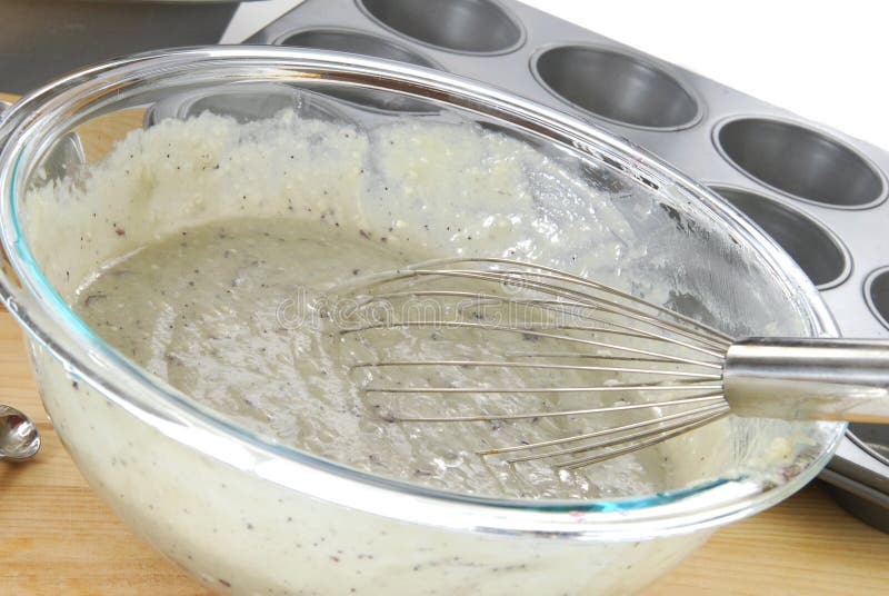 A bowl of blueberry muffin batter and muffin tins. A bowl of blueberry muffin batter and muffin tins