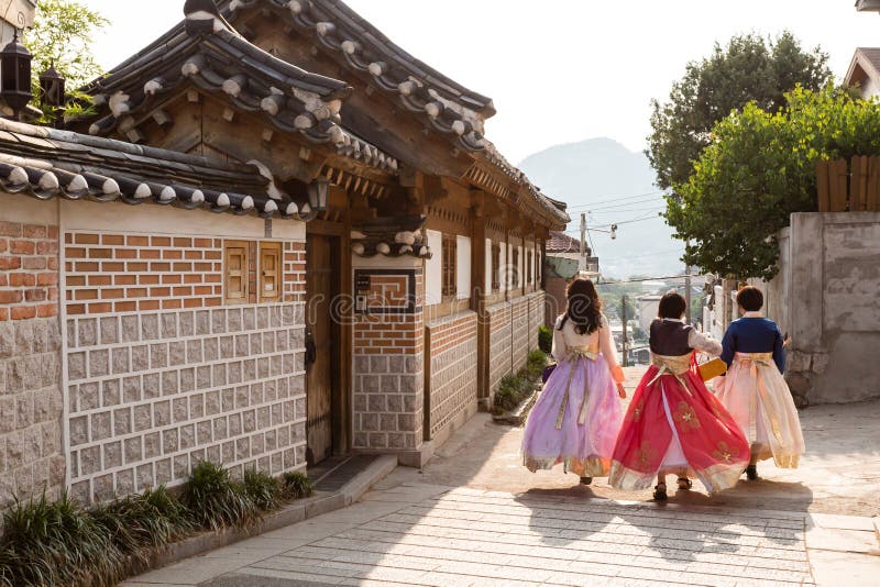 韩国首尔 — 2017年6月21日:三位年轻女性穿着色彩鲜艳的传统服饰 — 汉福在北川街上散步 免版税库存图片 韩国首尔 — 2017年6月21日:三位年轻女性穿着色彩鲜艳的传统服饰 — 汉福在北川街上散步 免版税库存图片
