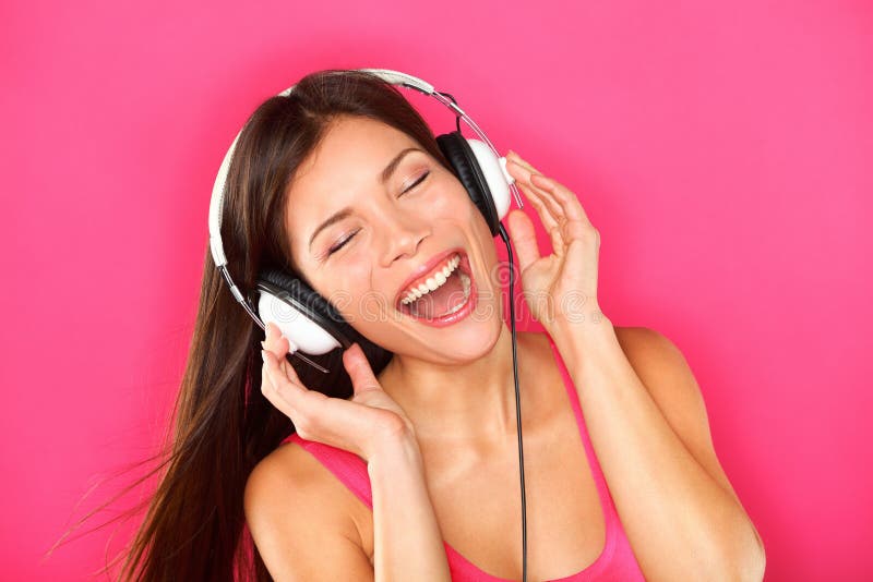 Music. Woman listening to music on headphones enjoying a dance. Closeup portrait of asian girl on pink background. Music. Woman listening to music on headphones enjoying a dance. Closeup portrait of asian girl on pink background