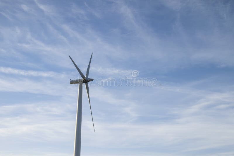 Wind turbine generating clean renewable energy, copy space, cirrus and blue sky. Wind turbine generating clean renewable energy, copy space, cirrus and blue sky