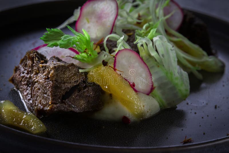 Close up view on Glazed Beef Cheek with celery puree and ginger pear on gray background in restaurant. Close up view on Glazed Beef Cheek with celery puree and ginger pear on gray background in restaurant