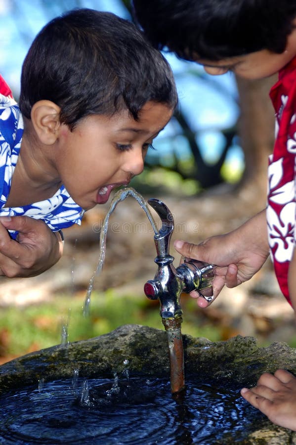 An Elder brother helpiong younger brother to drink water. An Elder brother helpiong younger brother to drink water