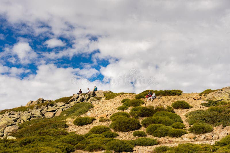 Madrid, Spain, 01/11/2020: Hikers sitting in the rocks resting. Ascent to Peñalara mount in the Sierra de Madrid. Madrid, Spain, 01/11/2020: Hikers sitting in the rocks resting. Ascent to Peñalara mount in the Sierra de Madrid