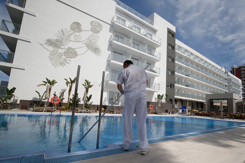 马略卡一家酒店的清洁工戴着防护面罩清洁游泳池