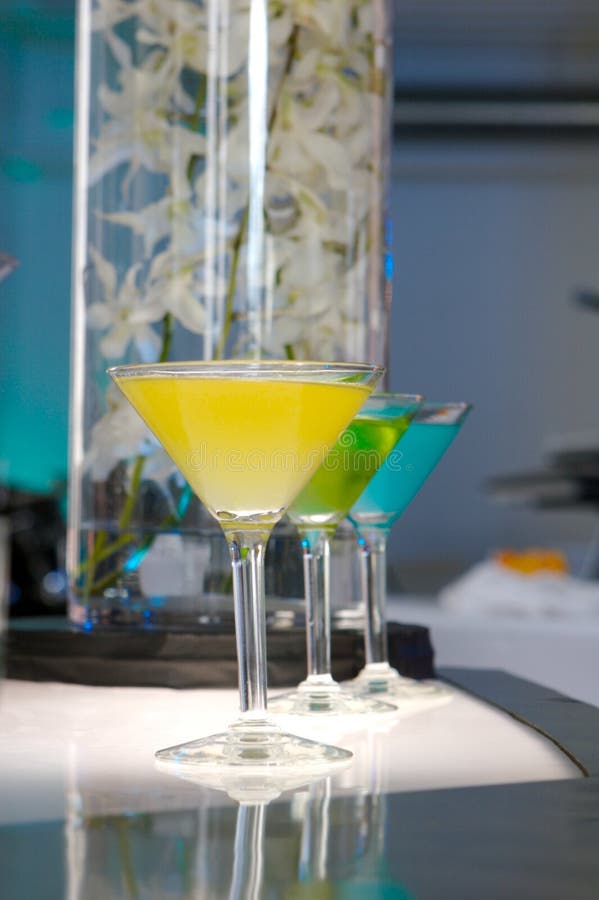 A yellow martini in front of a green and blue martini. A yellow martini in front of a green and blue martini