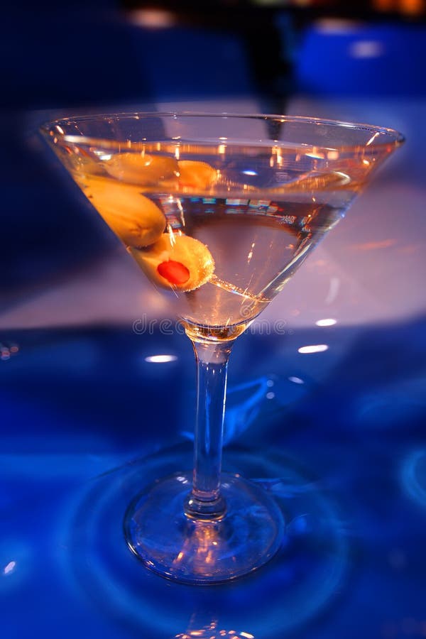 MARTINI WITH OLIVES ON A BLUE BACKGROUND FOOD AND BEVERAGE. MARTINI WITH OLIVES ON A BLUE BACKGROUND FOOD AND BEVERAGE