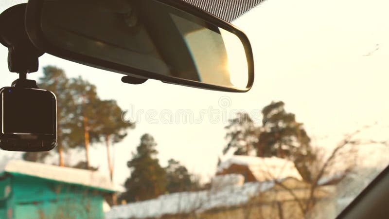 驾驶汽车在慢动作的冬天乡下 在后视镜的日落太阳