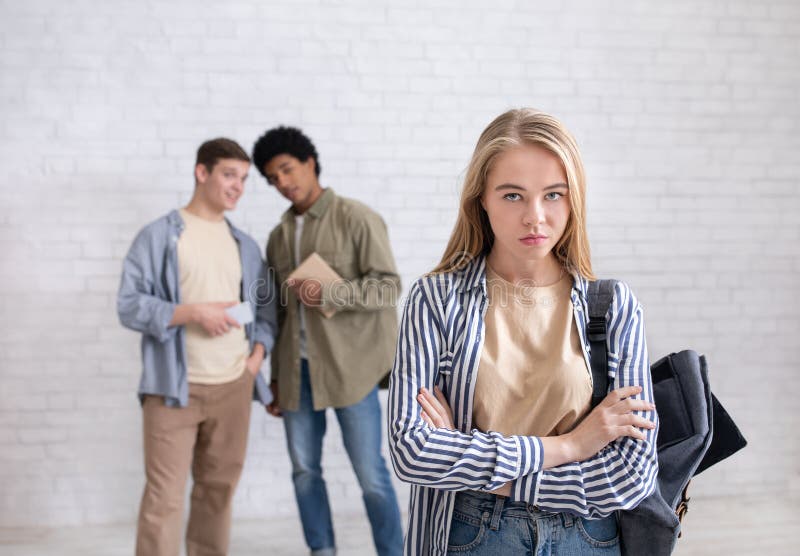 High school lady being bullied, pressure and humiliation by classmates. Multiracial teen males offend upset lady with backpack in school or college, on white wall background, studio shot, empty space. High school lady being bullied, pressure and humiliation by classmates. Multiracial teen males offend upset lady with backpack in school or college, on white wall background, studio shot, empty space