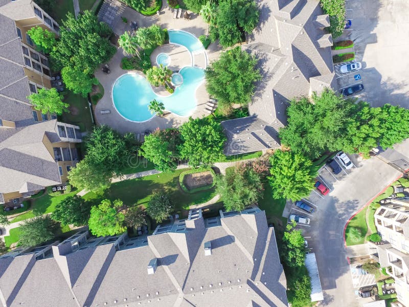 Top view typical multi-level apartment complex with swimming pool. Aerial green tree surrounded garden, rows of cars in parking lots. Residential recreation concept in Houston, Texas, USA. Top view typical multi-level apartment complex with swimming pool. Aerial green tree surrounded garden, rows of cars in parking lots. Residential recreation concept in Houston, Texas, USA