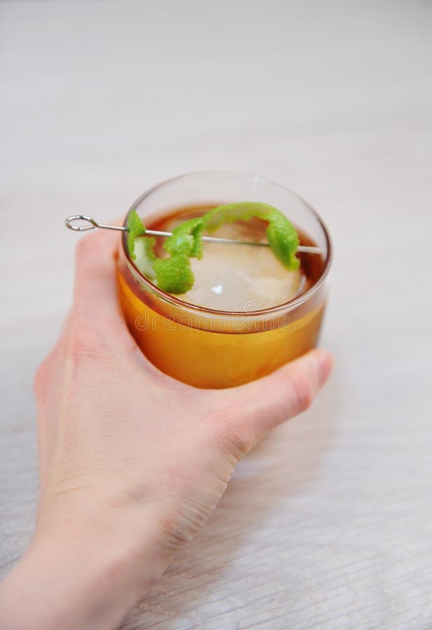 鸡尾酒威士忌酒与石灰的兰姆酒可乐和冰一个整个圆的片断 在手中轻的木表面上 库存图片 鸡尾酒威士忌酒与石灰的兰姆酒可乐和冰一个整个圆的片断 在手中轻的木表面上 库存图片