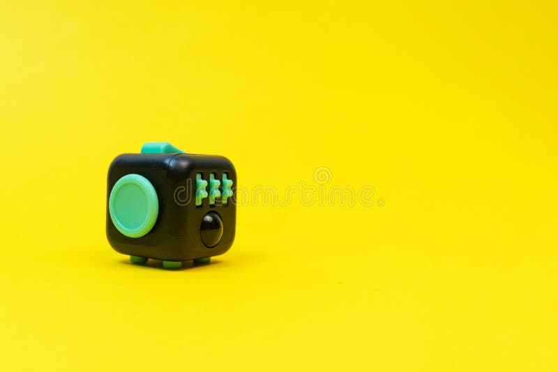 黄色背景上的黑色和绿色fidget立方 免版税库存图片 黄色背景上的黑色和绿色fidget立方 免版税库存图片