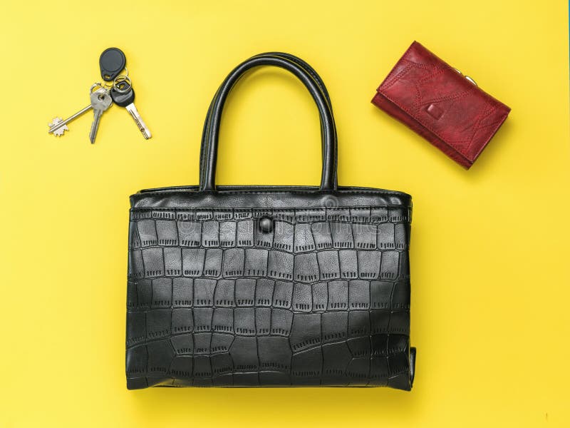 Black women`s bag and red purse on a yellow background. Fashionable leather women`s accessories. Flat lay. Black women`s bag and red purse on a yellow background. Fashionable leather women`s accessories. Flat lay.