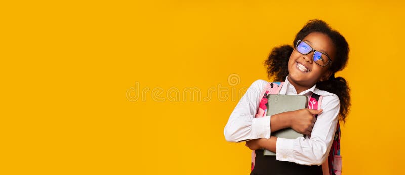 Positive Black Schoolgirl Embracing Book On Yellow Background. Happy Back To School. Free Space, Studio Shot, Panorama. Positive Black Schoolgirl Embracing Book On Yellow Background. Happy Back To School. Free Space, Studio Shot, Panorama