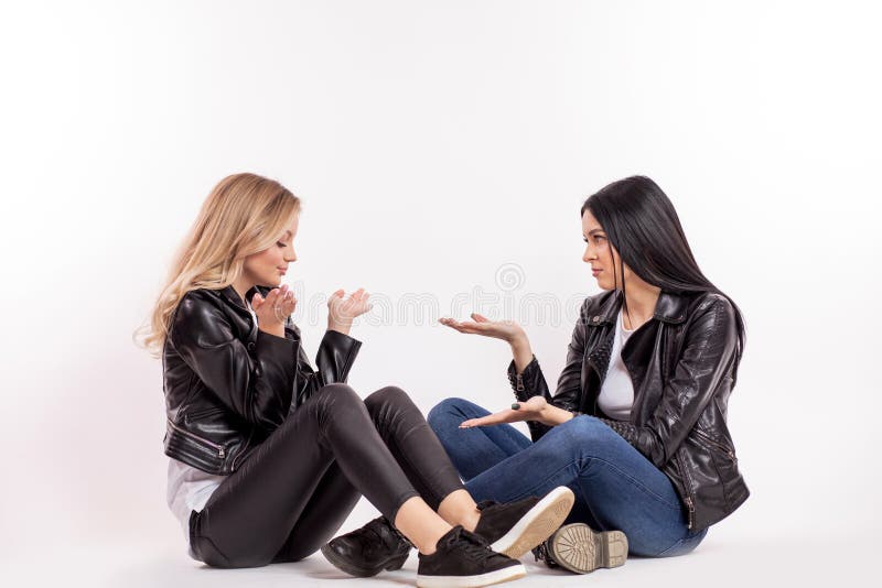 黑皮夹克的谈论两个迷人的女性的朋友某事 免版税库存照片 黑皮夹克的谈论两个迷人的女性的朋友某事 免版税库存照片