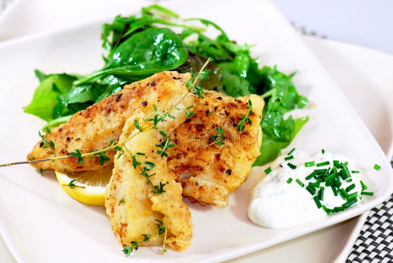 Beer-battered haddock fillets with fresh thyme on wild rocket salad and creme fraiche. Beer-battered haddock fillets with fresh thyme on wild rocket salad and creme fraiche