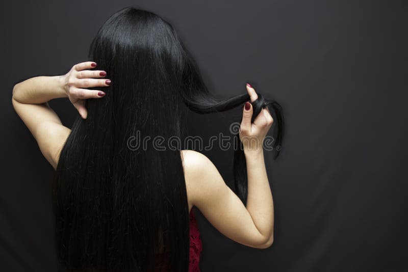 黑色背景上红衣中黑长发的美女 头发光滑，手很漂亮 库存照片