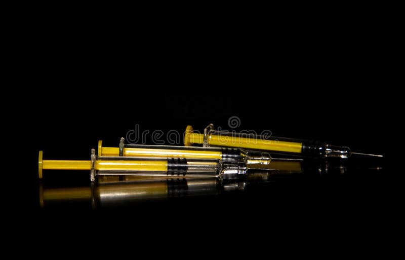 Close-up of multiple syringes on a dark surface. Close-up of multiple syringes on a dark surface