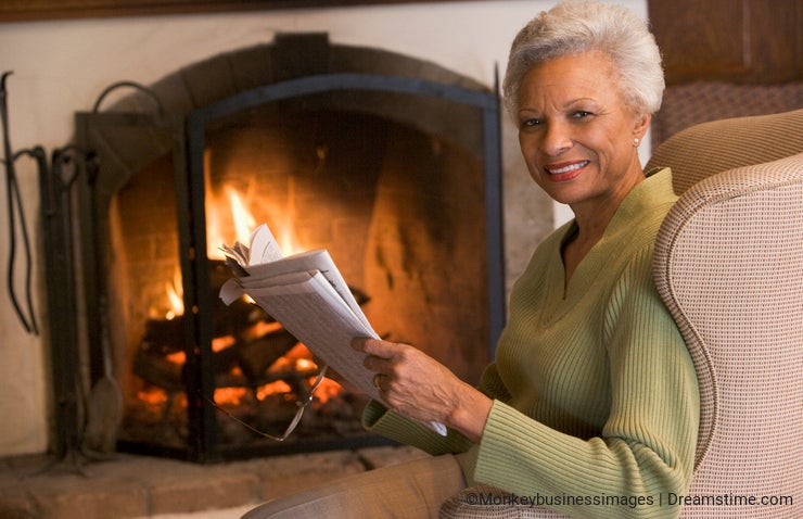 Woman sitting in living room by fireplace