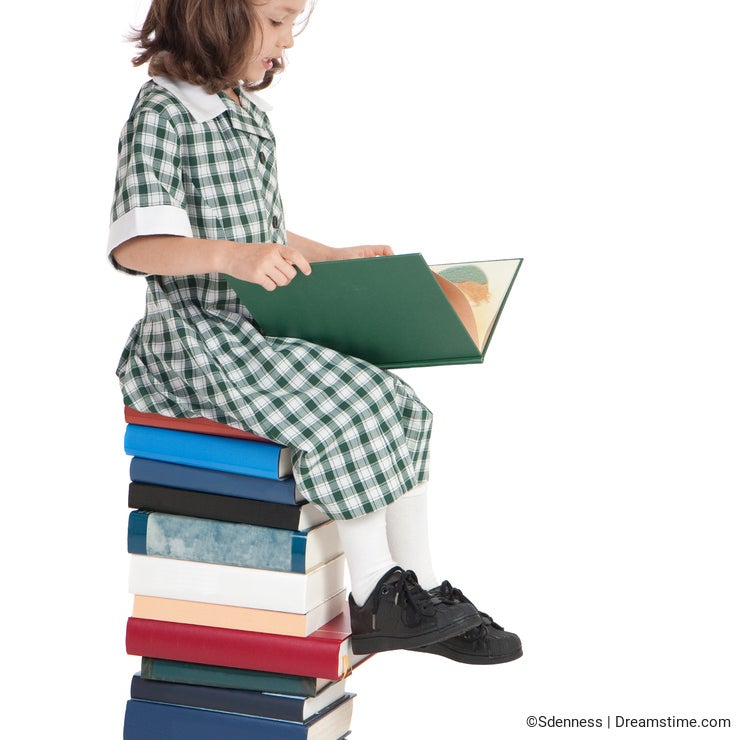 School girl sitting on book pile reading