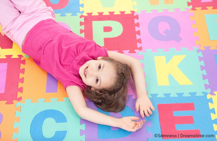 Smiling girl lying on alphabet tiles