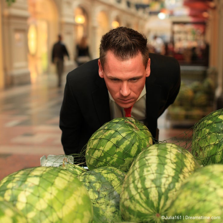Man smelling watermellons in shopping-centre