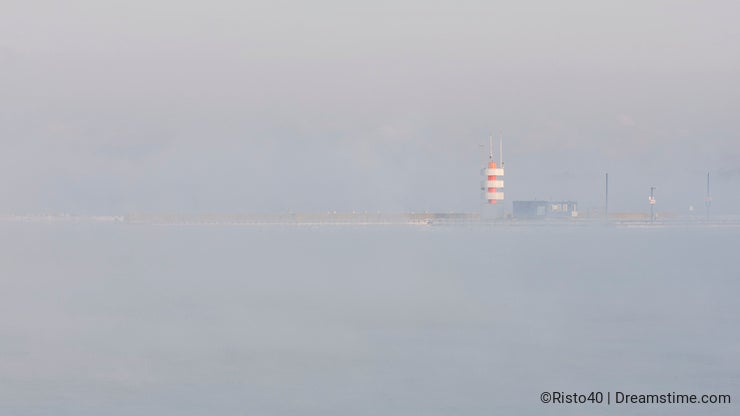 A lighthouse in the mist near sea
