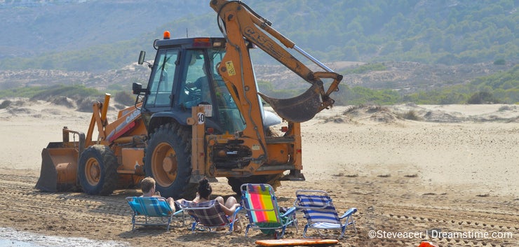 Beach Repairs - JCB CAT Digger At Seaside With Sunbathers And Holidaymakers