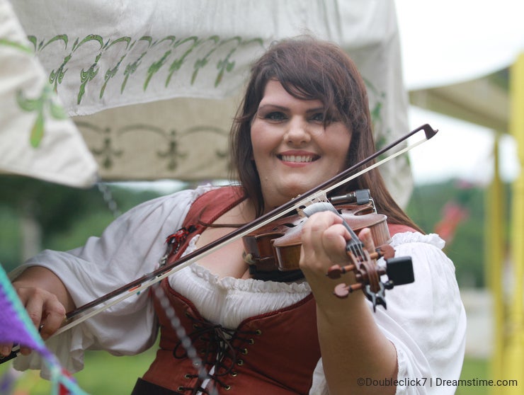 Renaissance Fair woman in costume plays fiddle
