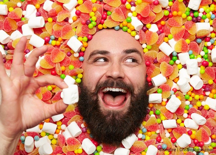 Cheerful man lying in sweet holding marshmallow