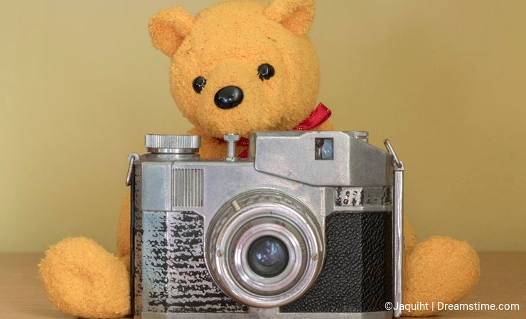 A yellow teddy bear with a camera