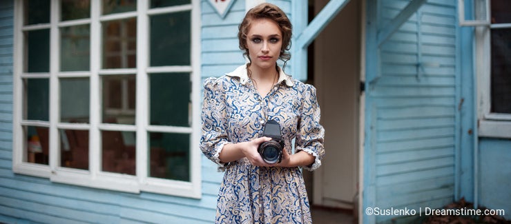 Woman in vintage dress with retro camera in hand